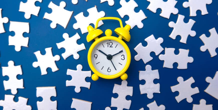 yellow-alarm-clock-and-white-puzzle-on-a-blue-back-2023-11-27-05-02-04-utc